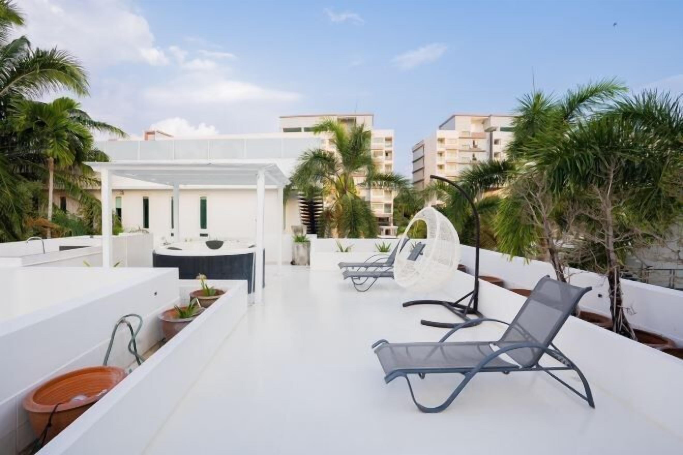 A rooftop terrace with a white pergola, lounge chairs, and potted plants.