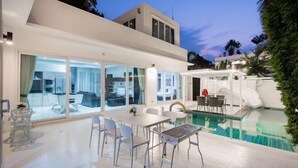 Ein modernes Haus mit Swimmingpool, großen Glasfenstern und einer Terrassenfläche.