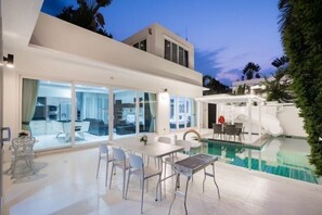 Une maison moderne dotée d’une piscine, de grandes portes vitrées et d’un espace patio.