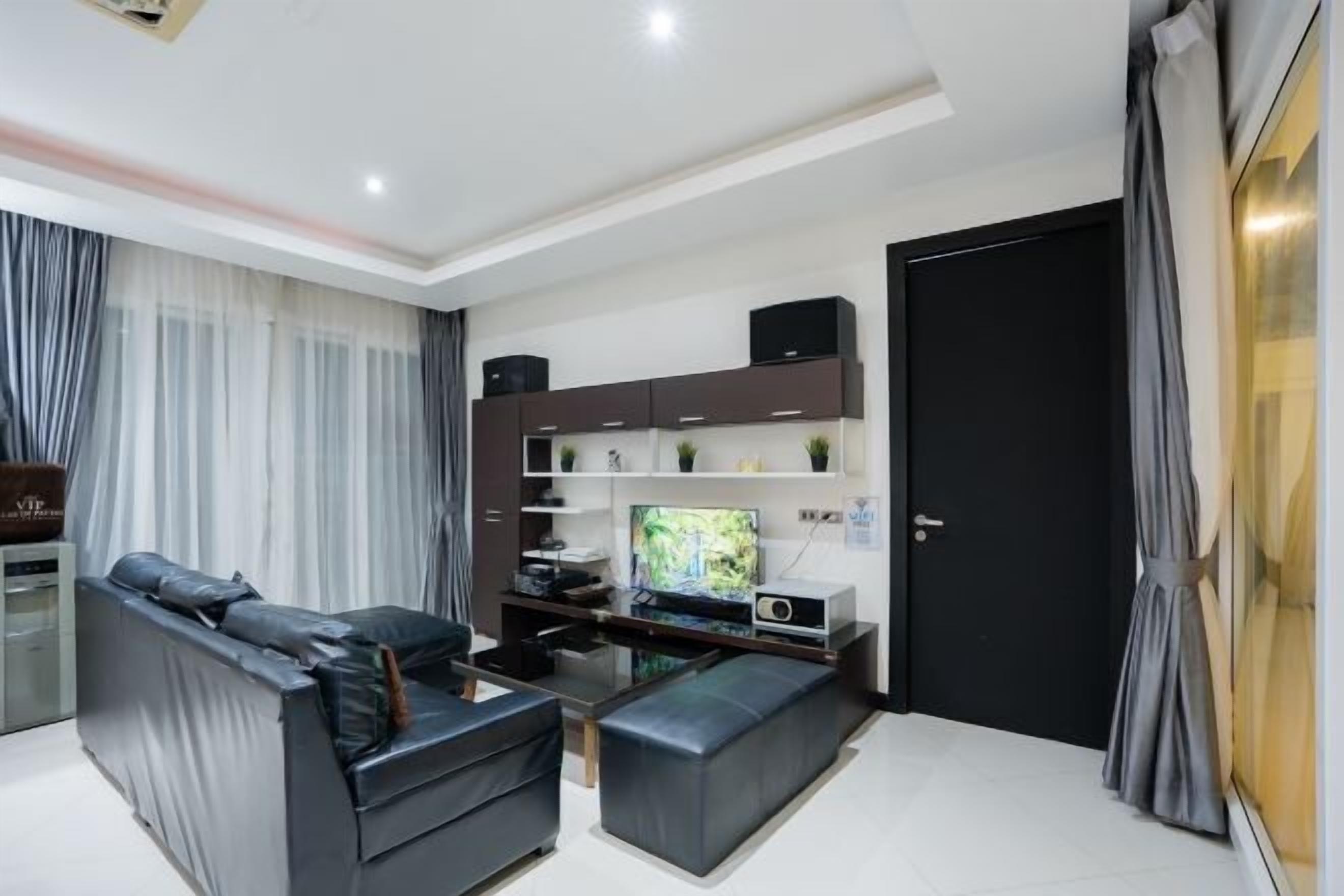 A modern living room with a sofa, a coffee table, a flat-screen TV, and built-in shelving.