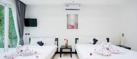 A hotel room with two beds, a flat-screen TV, a painting, and a small table with flowers.