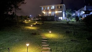 A modern two-story building with a well-lit exterior and a stone pathway leading to it. - MyGarden Nam Phuong Lakeview (Bao Loc)