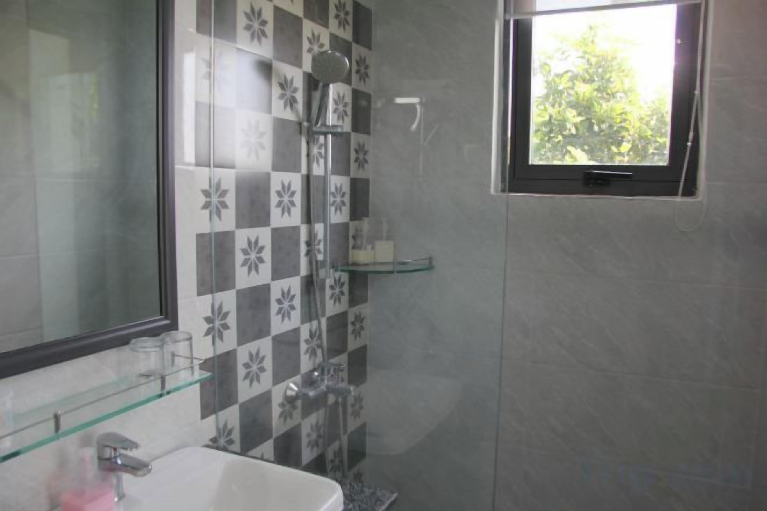 A bathroom with a shower, a sink, and a window.