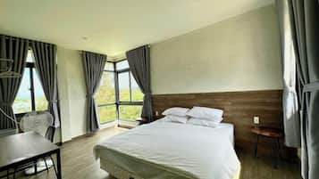 Habitación de hotel con una cama grande, un escritorio y una silla. Cuenta con ventanas con cortinas y vistas al exterior.