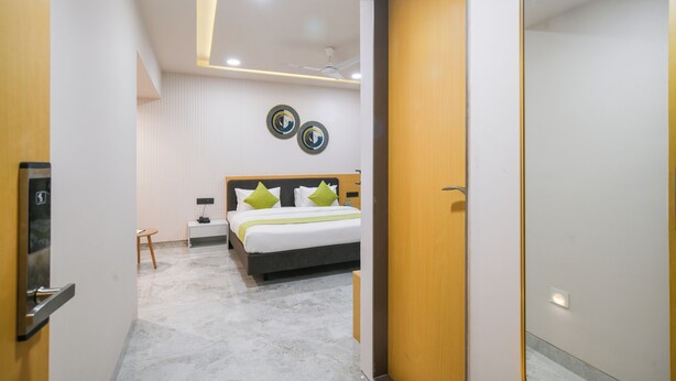 Una habitación de hotel moderna con una cama, mesita de noche y una obra de arte colgada en la pared.