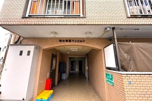 A building entrance with a sign above the door, a covered walkway, and a utility box to the left. - 【Color Nook1】Central Tokyo 15min／Narita 1hr！Station 10min walk！Newly renovated apartment (Tokyo)
