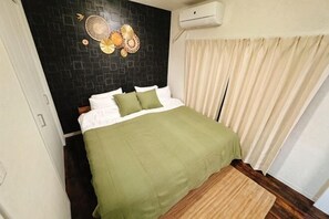 Un dormitorio con cama, aire acondicionado de pared y ventana con cortinas.