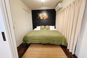 A bedroom with a bed, a wall-mounted air conditioner, and a door.