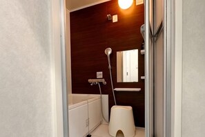 Ein Badezimmer mit Badewanne, Toilette, Dusche und Spiegel.