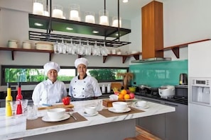 A modern kitchen with two chefs, a marble countertop, and a view of the outdoors. - Hi At Home Villa 4 (Pattaya)