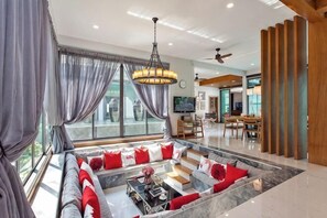 A modern living room with a sofa set, a coffee table, and a dining area in the background. - Hi At Home Villa 4 (Pattaya)