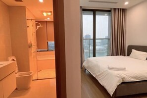 Une chambre d’hôtel avec un grand lit, une salle de bain avec douche et une vue sur la ville par la fenêtre.