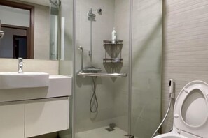Une salle de bain moderne avec une douche à parois de verre, un lavabo blanc et des toilettes.