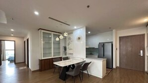 A modern kitchen with a built-in refrigerator, a dining area with a marble table and chairs, and a large window providing natural light. - Warm 4-Bedroom Apartment At Vinhomes Skylake (Hanoi)