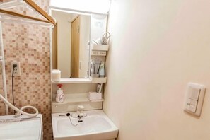 Une salle de bain avec un lavabo, un miroir et un mur recouvert de carreaux.