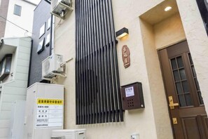 A building facade with a vertical black panel, a door with glass panels, and a sign with Japanese characters. - Yoshifukuya (Osaka)