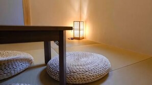 Tatami szőnyegek, egy alacsony asztal és egy a falra szerelt lámpatest.
