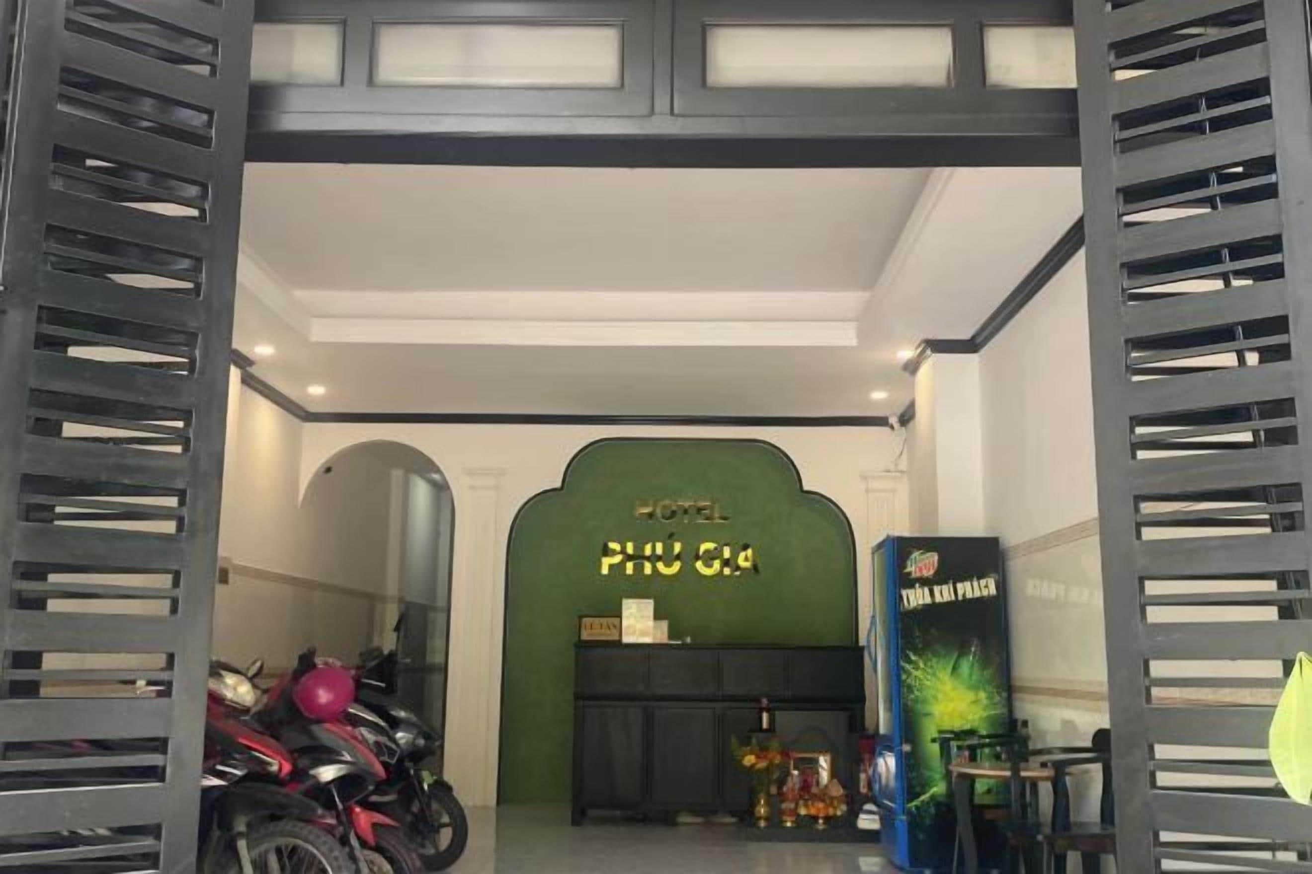 A hotel entrance with a green archway, a reception desk, and a motorcycle parked to the left.
