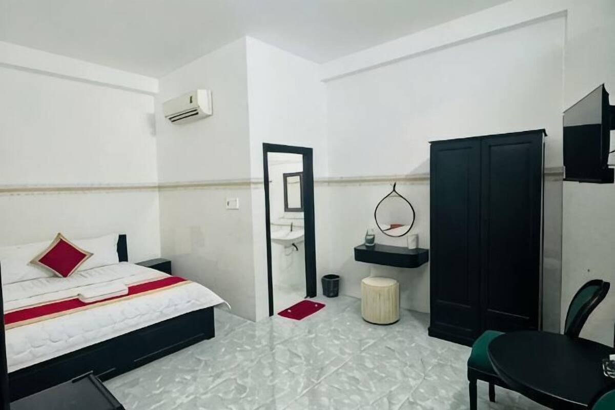 Ein Schlafzimmer mit Bett, Spiegel, Kleiderschrank, einem kleinen Tisch und einem Stuhl.