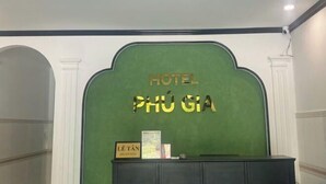 A reception area with a green backdrop and a sign that reads "HOTEL PHÚ GIÁ". - Phú Gia Hotel Phu My Quan 7 (Ho Chi Minh City)