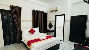 A hotel room with a bed, a desk, a chair, a wardrobe, and a door. - Phú Gia Hotel Phu My Quan 7 (Ho Chi Minh City)
