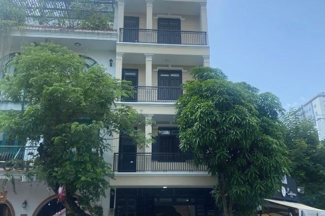 A multi-story building with balconies and a tree in front.