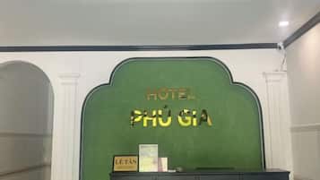 A reception desk with a green backdrop and the text 'HOTEL PHU GIÀ' above it.