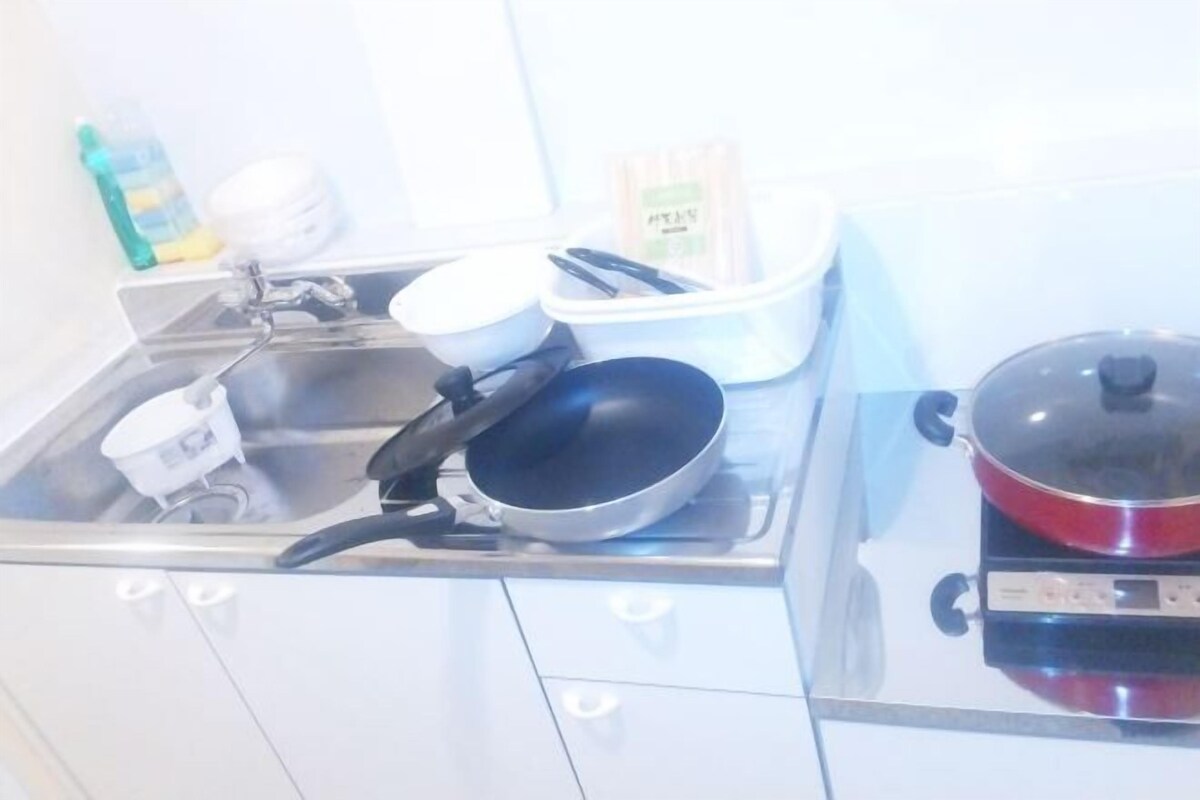 A kitchen with a stove, a sink, and various kitchen utensils.