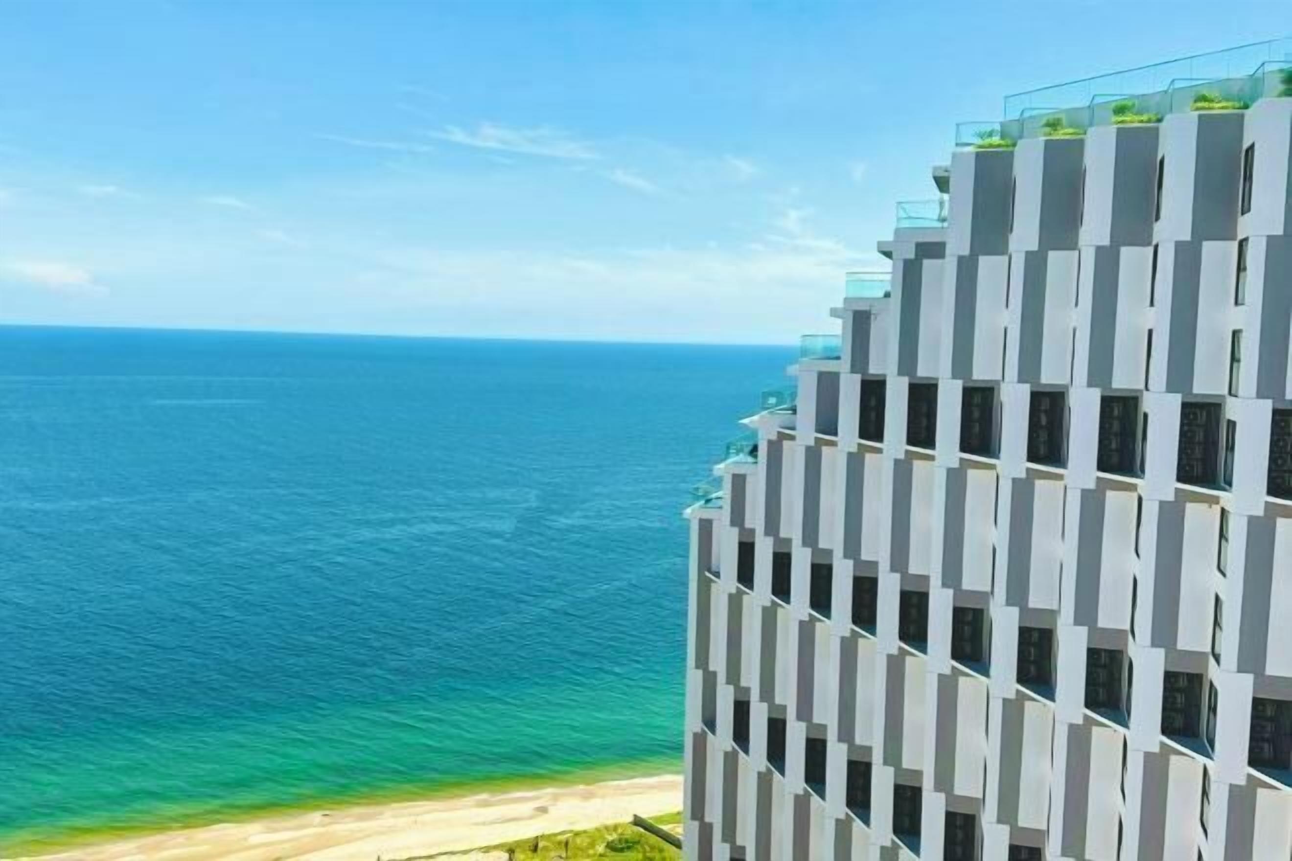 Un hotel moderno de gran altura con una fachada geométrica distintiva, con vistas a una playa y al océano.