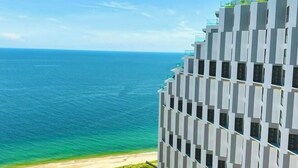 Ett modernt hotell i en hög byggnad med en unik, geometrisk fasad, med utsikt över en strand och havet.