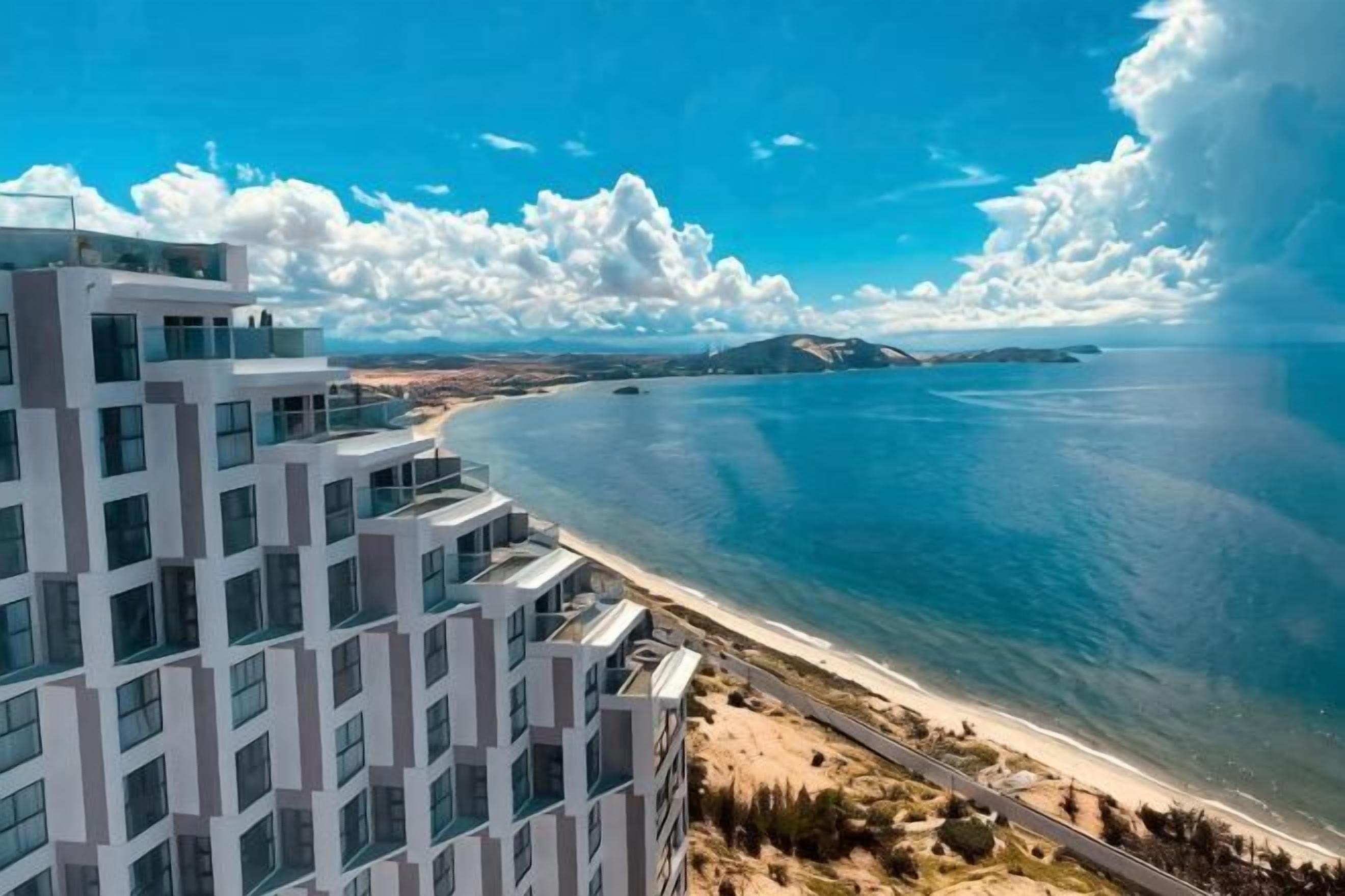 Un edificio moderno de varios pisos, vista al mar y cielo despejado.