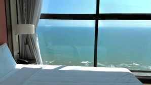 Ett hotellrum med ett stort fönster, en säng och gardiner.