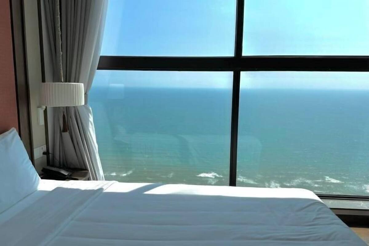 Una habitación de hotel con un ventanal grande, una cama y cortinas.