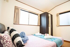 A bedroom with a bed, a wardrobe, and two windows. - Shinjuku Everlasting Cabin (Tokyo)