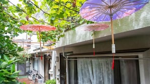 A narrow corridor with a tiled floor, a bicycle parked at the end, and a window with a curtain. - Shinjuku Everlasting Cabin (Tokyo)