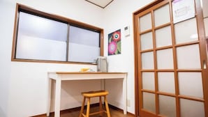 A room with a white desk, a wooden stool, a window, and a sliding door with frosted glass panels. - Shinjuku Everlasting Cabin (Tokyo)