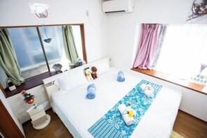 A bedroom with a bed, a bedside table, a small desk, and a window with curtains. - Shinjuku Everlasting Cabin (Tokyo)
