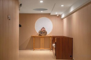 Un couloir avec un comptoir d’accueil, un miroir rond et un banc en bois.