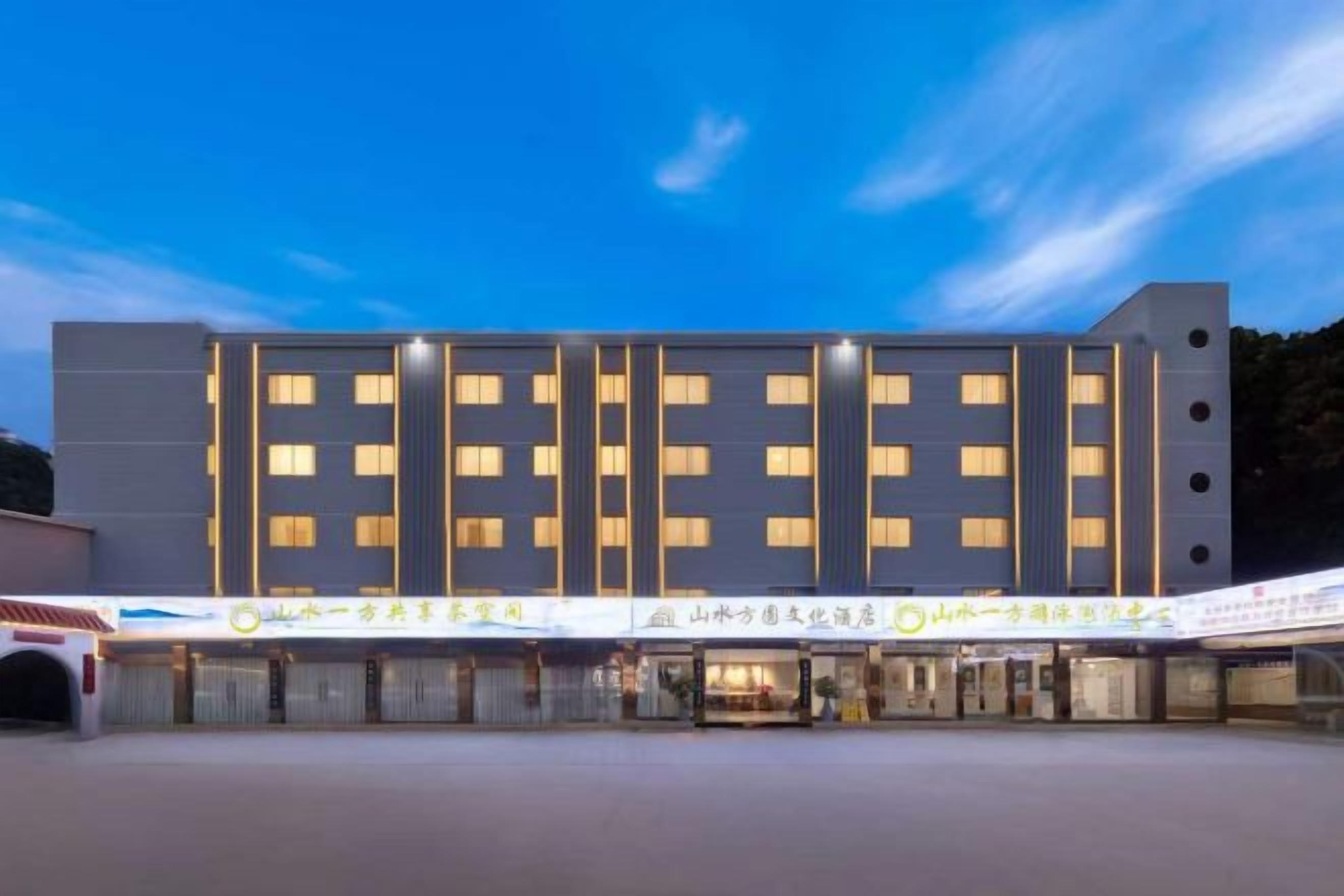 Een modern hotel met een symmetrische gevel, meerdere verdiepingen en een rij ramen.