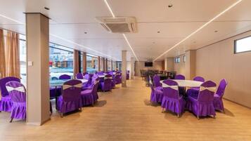 Un salón de conferencias con filas de mesas y sillas, ventanas amplias y un diseño de interiores moderno.