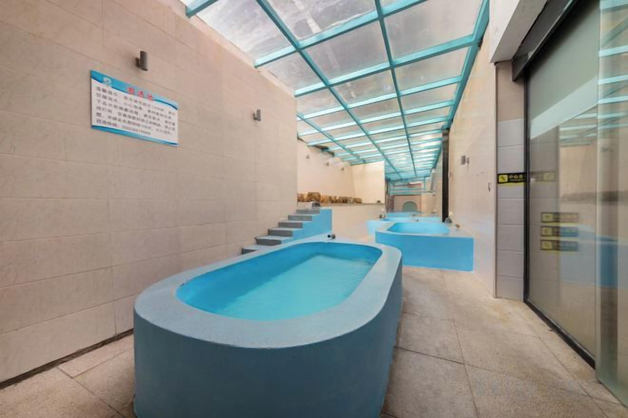 A swimming pool area with a glass ceiling, a staircase, and a sign on the wall.