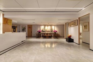A hotel reception area with a reception desk, a seating area with a table and chairs, and a wall with framed artwork. - Resort Hotel on the landscap (Xiamen)