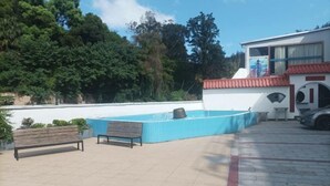 An outdoor area with a pool, benches, and a building with a red roof. - Resort Hotel on the landscap (Xiamen)