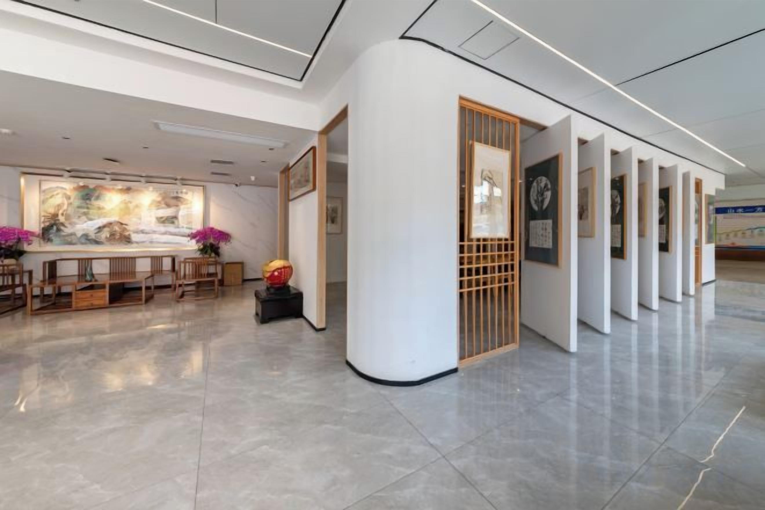 A modern lobby with a reception desk, framed artwork, and a seating area.