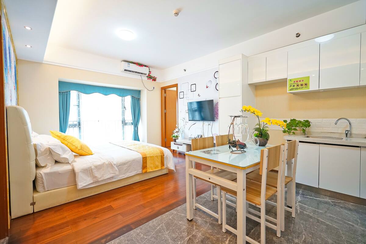 Ein modernes Zimmer mit einem Bett, einem Esstisch und einer Küchenzeile.