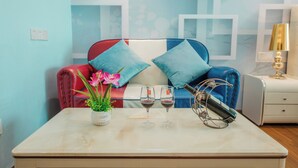 A room with a sofa, two wine glasses, a bottle, and a small table with a vase of flowers. - TUXI INTERNATIONAL APARTMENT (Guangzhou)