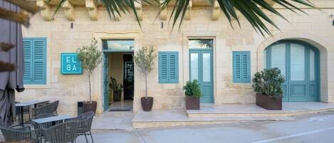 A building with a stone facade, green shutters, and outdoor seating.