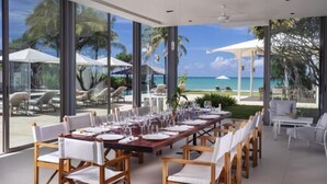 A dining area with a view of the beach, large windows, and outdoor seating. - Sava Villa 5 Villa Malee Sai (Takua Thung)