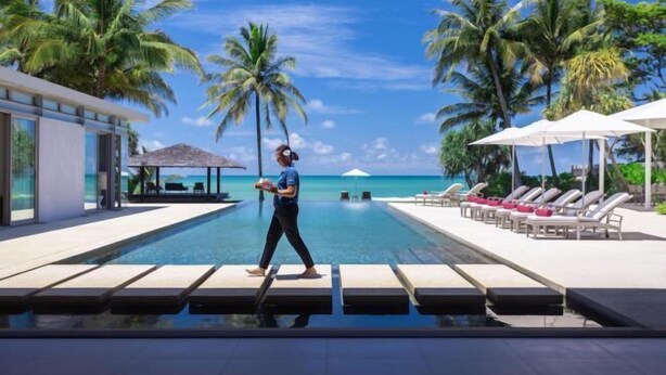 A poolside area with lounge chairs and umbrellas, palm trees, and a view of the ocean. - Sava Villa 5 Villa Malee Sai (Takua Thung)