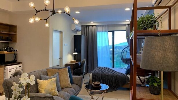 A modern living room with a sofa, coffee table, and a hanging light fixture. - Deluxe Holiday Studio Suite @ Timurbay w/ Seaview (Kuantan)